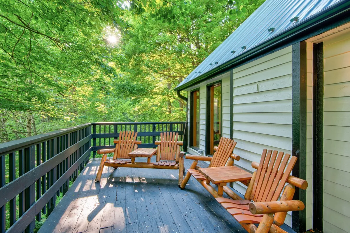The hero image showcases the exterior of a spacious mountain home, with inviting wooden chairs set on a deck overlooking lush greenery. The peaceful setting hints at opportunities for relaxation, whether enjoying the sunrise, stargazing, or gathering for outdoor meals.